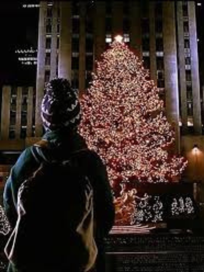 Kevin standing in front of the Rockefeller Center Christmas Tree lit up in New York City during the winter holiday season